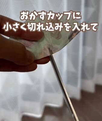 半分に折ったおかずカップの真ん中にハサミで切り込みを入れる様子