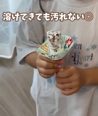 女の子がおかずカップを付けた棒アイスを持っている様子