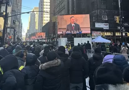 今年1月1日、米ニューヨーク市庁舎で就任演説を行なったマムダニ市長。周辺の路上でその中継画面を見つめるニューヨーカーたち