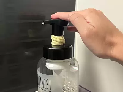 ヘアゴムをつけたボディソープのボトルを押す場面(撮影:grapeライフハック編集部)