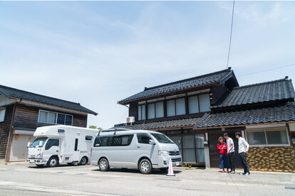 石川県穴水町川尻に位置する「田舎バックパッカーハウス」の 初代「バンライフ・ステーション」自身の部屋は車（手前）、家屋の共有スペースや設備を利用することが可能