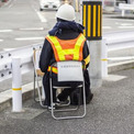 道路脇のパイプ椅子に座って何か数えている人…何してるの？